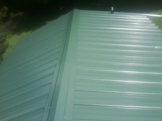 New green metal panels meeting at the ridge of a roof — Flat Roof Repair work by our crew in Republic