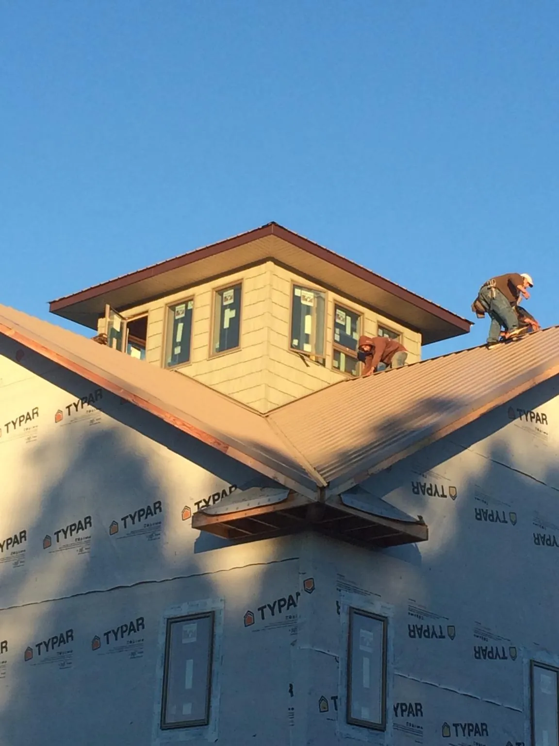 Roofers working around a rooftop cupola on a new metal roof at sunset — Roof Waterproofing in Republic by Roofing Brothers